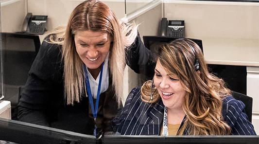two smiling women at desk
