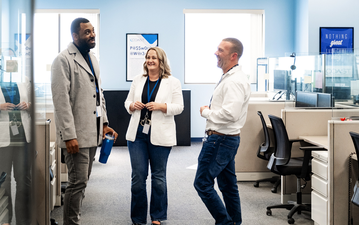 Three employees standing and chatting